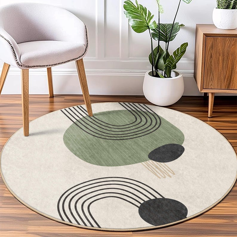 May include: A round, cream-colored rug with a geometric design featuring black lines and green and black circles. The rug has a subtle texture and a fringe border.