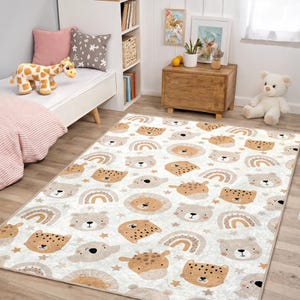 Könnte beinhalten: Rechteckiger Teppich mit einem sich wiederholenden Muster aus Cartoon-Tiergesichtern, Regenbogen und Sternen in Braun-, Beige- und Cremetönen. Der Teppich liegt auf einem Holzboden in einem Kinderzimmer.
