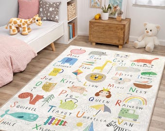 May include: A rectangular children's rug with an alphabet design. Each letter is paired with a colorful illustration of an animal or object, such as an elephant, zebra, and rainbow. The rug is cream-colored and placed on a wooden floor.