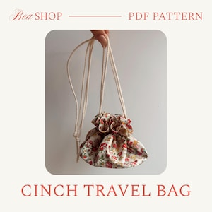 May include: A floral print cinch travel bag with a drawstring closure. The bag is held by a cream-colored cord. The bag's fabric features a pattern of red, yellow, and green flowers on a cream background. The text "Bea SHOP PDF PATTERN CINCH TRAVEL BAG" is displayed.