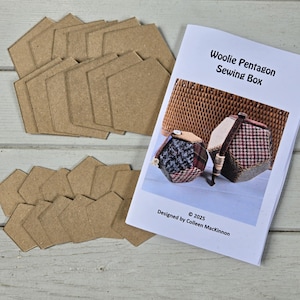 May include: A craft project with brown cardboard pentagons and a booklet titled "Woolie Pentagon Sewing Box." The booklet shows two finished fabric boxes with patterned designs. The text "Designed by Colleen MacKinnon" is also visible.