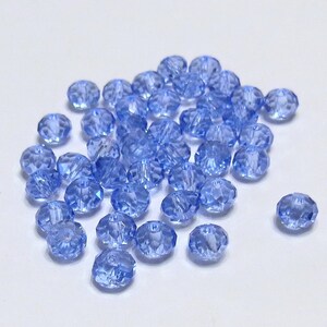 May include: A pile of light blue faceted glass beads. The beads are small and round, with a shiny finish.