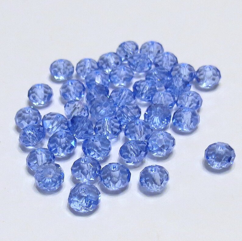 May include: A pile of light blue faceted glass beads. The beads are small and round, with a shiny finish.