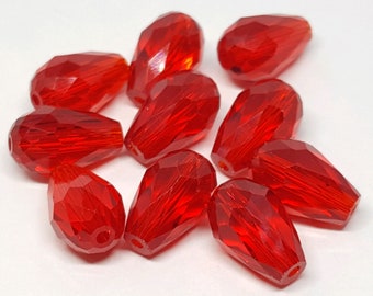 May include: A collection of faceted, teardrop-shaped beads in a vibrant, transparent red. The beads are scattered on a white surface, showcasing their multiple reflective surfaces and glossy finish. These beads are suitable for jewelry making.