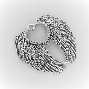 May include: Silver-toned metal charm featuring a heart-shaped cutout framed with small beads, flanked by detailed wing designs. The wings have a textured, feathered appearance, and the charm has a loop at the top for attachment. Ideal for jewelry making.