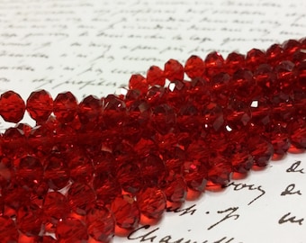May include: A strand of red faceted glass beads. The beads are round and have a shiny finish.