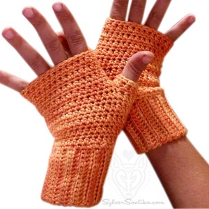 Pode incluir: Um par de luvas sem dedos de crochê laranja com punho canelado. As luvas são feitas com um padrão de ponto simples.