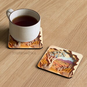May include: Two square wooden coasters with a desert landscape design. The coasters feature a layered paper art style with a 3D effect. One coaster has a single tree in the center, while the other has a more expansive view of the desert.