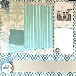 May include: A scrapbook page with a light blue and white color scheme. It features patterned paper, including stripes and floral designs. Decorative elements include a camera illustration, a bird, and the text "THE GOOD LIFE".