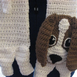 May include: White crocheted scarf with a brown and white crocheted dog head attached. The dog has black eyes and a black nose.