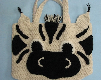 May include: A crocheted zebra-shaped tote bag with black and white stripes and a black face. The bag has two handles and a small mane on top.