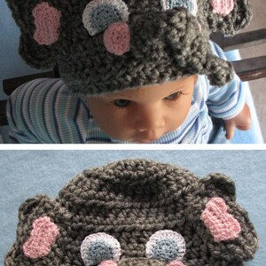 May include: Gray crocheted elephant hat with pink and blue accents. The hat has a long trunk and large ears.