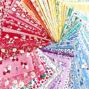 Op de afbeelding: Een kleurrijke waaier van stofstalen, gerangschikt in een cirkelvormig patroon. De stoffen tonen diverse bloemen- en patroonontwerpen in een spectrum van kleuren, waaronder rood, roze, oranje, geel, groen, blauw en paars. Geschikt voor patchwork of knutselprojecten.