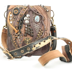 Puede incluir: Un bolso bandolera de cuero marrón con un diseño único que presenta múltiples capas de cuero, tachuelas y detalles metálicos. El bolso tiene una correa larga ajustable y un cierre de solapa.