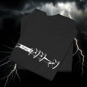 May include: Two black t-shirts with a white graphic design. The design features a knife piercing through a series of hearts, with the word "Kader" on the knife and the initials "FW", "IF", and "OS" on the hearts.