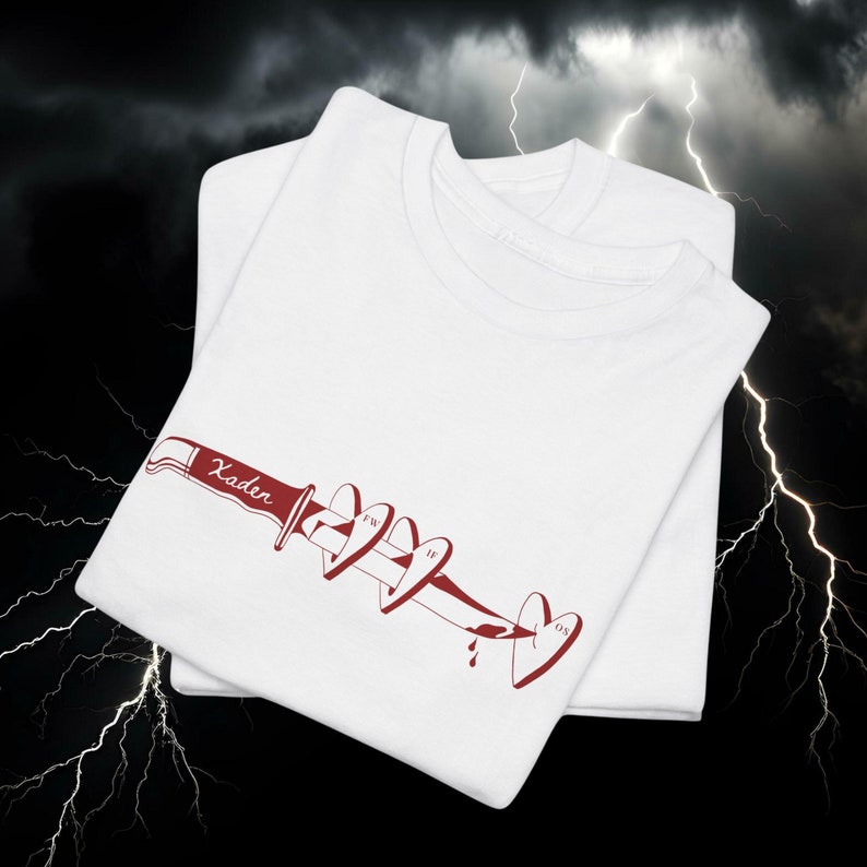May include: Two white t-shirts are stacked, each with a red graphic of a knife piercing hearts. The knife handle reads "Xader". The hearts display the initials "FW", "IF", and "OS".