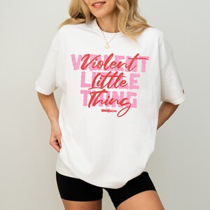 May include: White oversized t-shirt with a pink and red graphic print that says "Violent Little Thing".