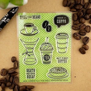 Pode incluir: Conjunto de carimbos transparentes com ilustrações e frases com tema de café. Os desenhos incluem uma xícara de café, grãos, um copo para viagem, uma bebida de café com chantilly e um donut. O texto inclui "Spill the Beans", "Need a Cuppa".