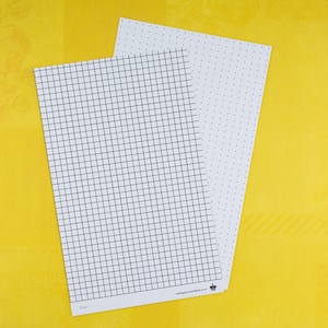 Peut inclure: Deux feuilles de papier blanches avec des motifs de grille et de points noirs, posées sur une surface jaune. Le papier quadrillé a des carrés de 5 mm. Le texte "wellappointeddesk.com" et un logo de couronne sont visibles.
