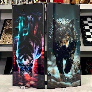 May include: Two-panel room divider featuring wolf artwork. One panel shows a wolf upside down with blue and red hues. The other panel depicts a wolf running through a snowy landscape. The divider is black with a glossy finish.