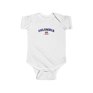 May include: White baby grow with blue text that says "COLOMBIA" with a small Colombian flag and the word "Soypata" underneath.