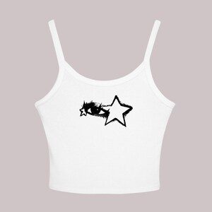 May include: White tank top with thin straps. The top features a black graphic design of an eye and a star. The eye and star design has a distressed, spray-painted aesthetic. The top is made of a soft, lightweight material.