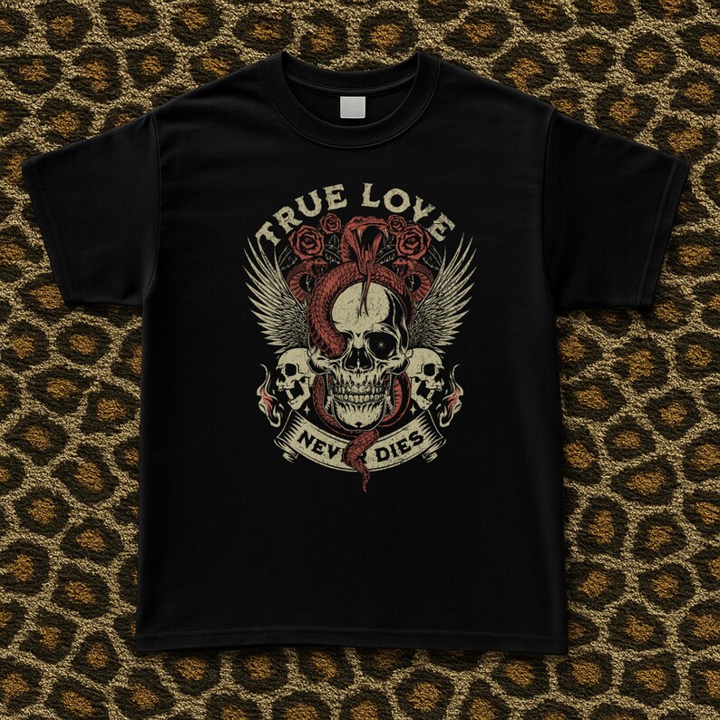 Pode incluir: T-shirt preta com um design de caveira, cobra, rosas e asas. O texto "TRUE LOVE NEVER DIES" &eacute; exibido acima e abaixo da caveira. O gr&aacute;fico &eacute; em tons de vermelho, branco e bege.