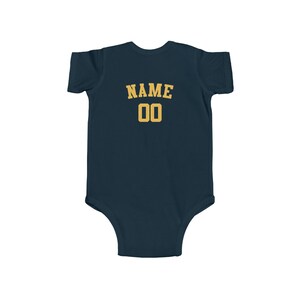 May include: A navy blue baby bodysuit with a gold "NAME 00" graphic on the back.