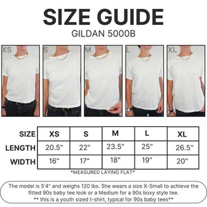 Peut inclure: Guide des tailles pour un t-shirt Gildan 5000B, avec des mesures en pouces pour les tailles XS &agrave; XL. Le guide comprend les dimensions de longueur et de largeur. Le mannequin mesure 163 cm et p&egrave;se 54 kg. Le texte en haut dit "SIZE GUIDE".
