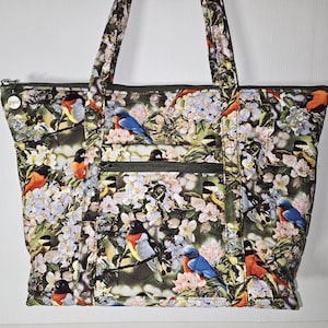 Bolso de tela acolchada con hermosos pájaros sobre un fondo de vegetación y flores.