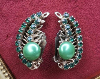 May include: A pair of vintage clip-on earrings with a green pearl center and a design of green rhinestones.