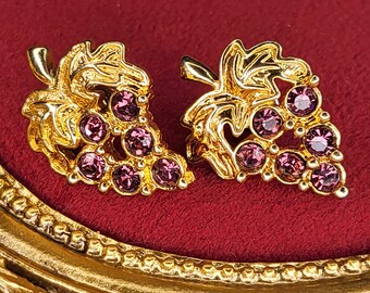 Könnte beinhalten: Ein Paar goldfarbene Ohrringe in Form von Trauben mit lila Strasssteinen.