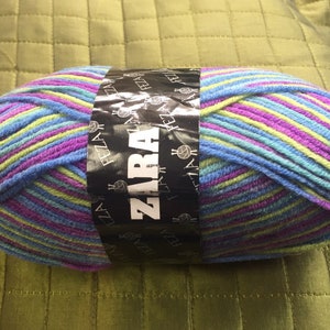 May include: A ball of yarn with blue, purple, green, and yellow stripes. The yarn is labeled "ZARA" and "FEZZA" on a black label.