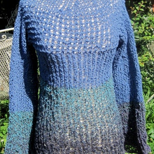 May include: A blue, teal, and gray ombre knitted sweater with a loose fit and long sleeves. The sweater has a lacy pattern throughout.