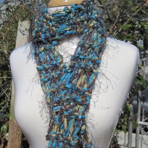 May include: A brown, blue, and beige knit scarf with a fuzzy texture. The scarf is looped around a white mannequin.