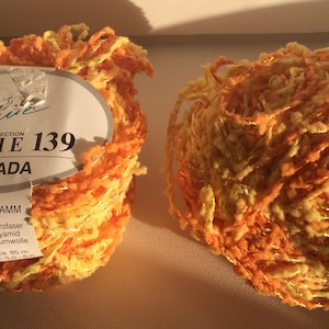 May include: Two balls of orange and yellow yarn with a label that reads "Trend Collection Linie 139 Cicada 50 Gramm 90% Microfaser Polyamid 10% Baumwolle ca. 85 m"