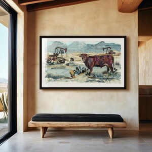 May include: A framed landscape print featuring a longhorn steer in the foreground of a desert scene with cacti, distant mountains, and oil pump jacks in the background. The artwork uses a muted color palette of browns, blues, and tans.