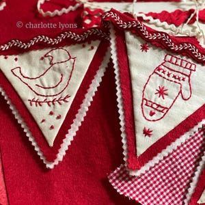 May include: A red and white felt Christmas garland with embroidered birds and mittens. The garland is decorated with white scalloped trim and red stitching.