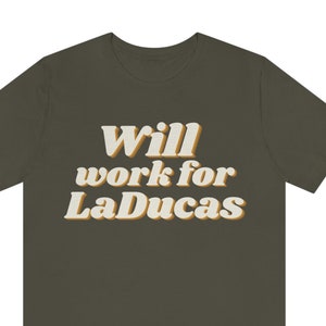 Op de afbeelding: Een donkergroen T-shirt met de tekst "Will work for LaDucas" in een retro-lettertype stijl.