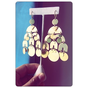 May include: A pair of gold-toned earrings with a geometric design. The earrings are made of multiple circular and semi-circular shapes, creating a cascading effect.