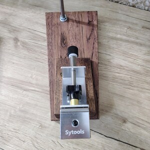May include: A wooden and metal tool with the text "Sytools" on a silver metal plate. The tool has a wooden base, a metal rod, and a black knob. The tool is designed for a specific purpose.