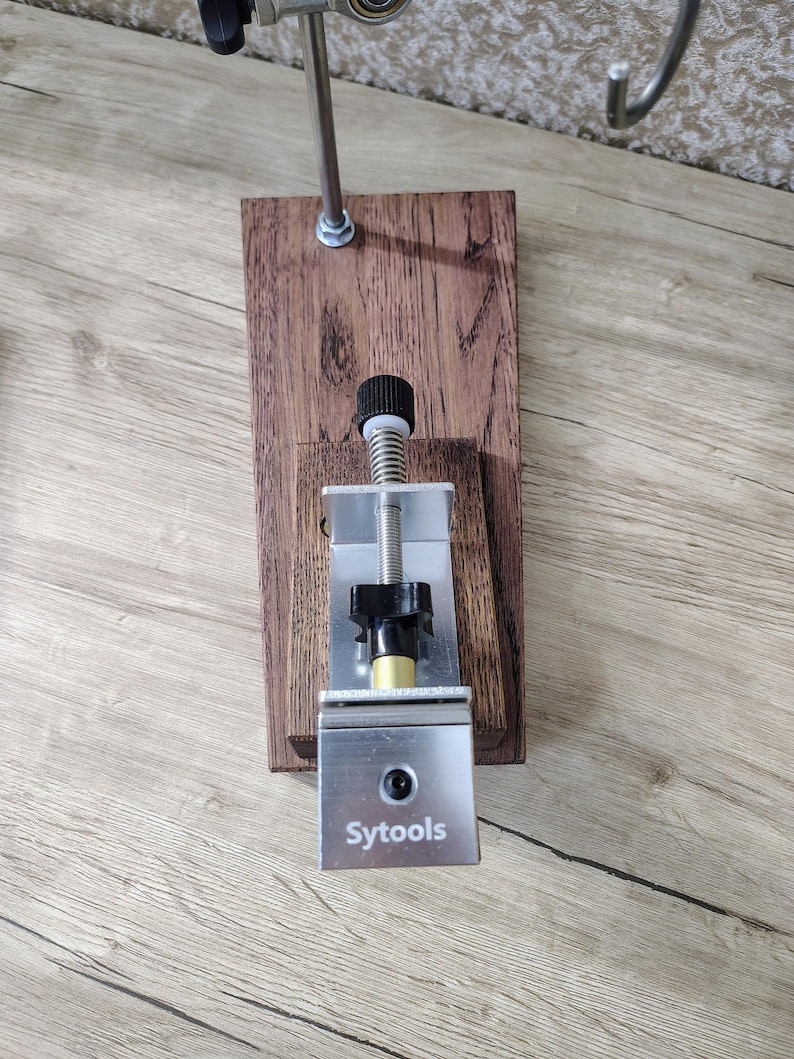 May include: A wooden and metal tool with the text "Sytools" on a silver metal plate. The tool has a wooden base, a metal rod, and a black knob. The tool is designed for a specific purpose.