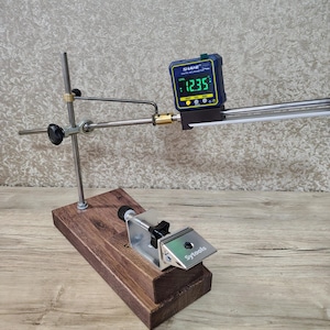 May include: A wooden and metal sharpening system with a digital inclinometer displaying 12.35 degrees. The system includes a base, a clamp, and adjustable arms. The brand name "Sytools" is visible on the clamp.