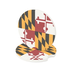 Könnte beinhalten: Zwei runde Untersetzer mit der Flagge des Bundesstaates Maryland. Die Untersetzer sind weiß mit einem rot-gelben Karomuster und einem rot-weißen Kreuz in der Mitte.
