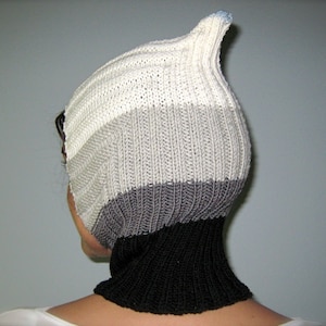 May include: A white, gray, and black knitted hat with a pointed top and a black neck warmer.