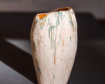 Ceramic vase, soft shape, matt white color and colored scratches pattern. irregular edge. may contain liquids
