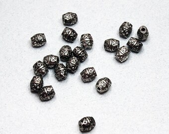 May include: A collection of silver metal beads with an intricate design. The beads are oval shaped and have a textured surface.