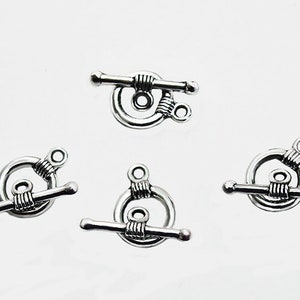 May include: Four silver-toned toggle clasps with a twisted wire design. Each clasp has a round ring and a bar with rounded ends.