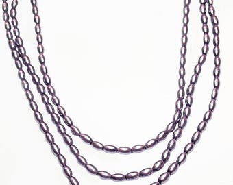 May include: A triple strand necklace made of purple oval beads.