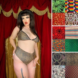 Puede incluir: Una mujer lleva un sujetador y ropa interior de cintura alta con estampado de leopardo. La ropa interior tiene un corte alto en las piernas. La mujer está de pie frente a una cortina de terciopelo rojo con flecos dorados.